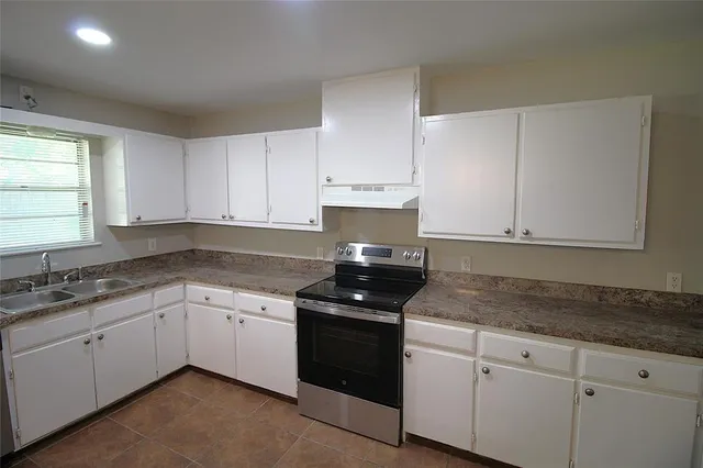 a kitchen with granite countertop white cabinets white appliances