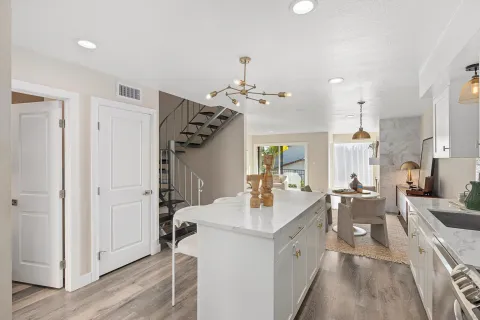 a large white kitchen with a lot of counter space and wooden floor