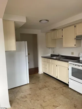 a kitchen with granite countertop a refrigerator and a stove top oven