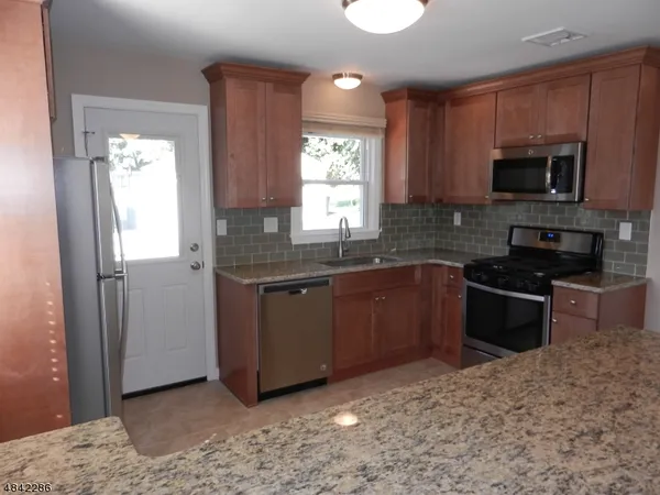a kitchen with granite countertop a refrigerator and a sink