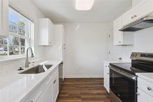 a kitchen with granite countertop a sink a stove and cabinets