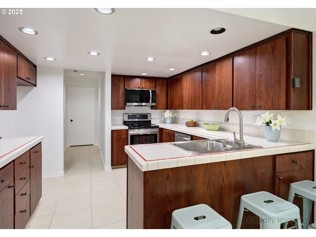 a kitchen with a sink a stove a refrigerator cabinets and a chairs