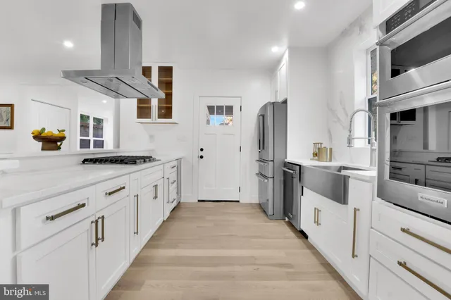 a large white kitchen with stainless steel appliances and cabinets
