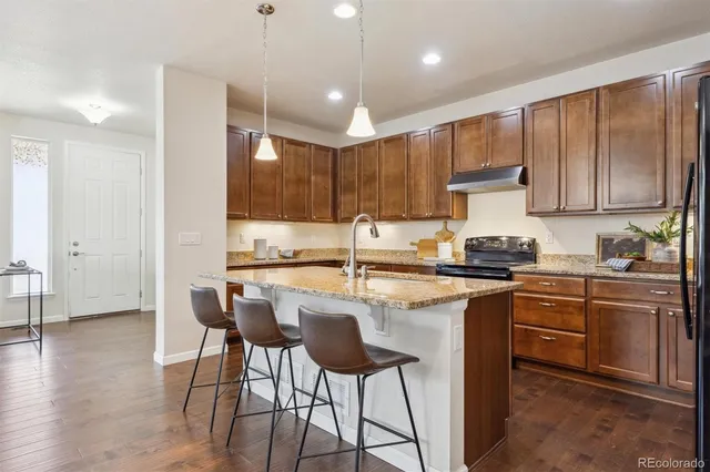a kitchen with kitchen island granite countertop wooden cabinets and a refrigerator