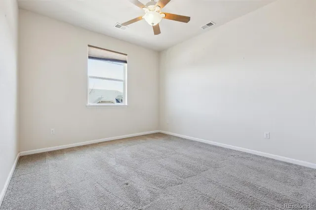 an empty room with a window and a fan