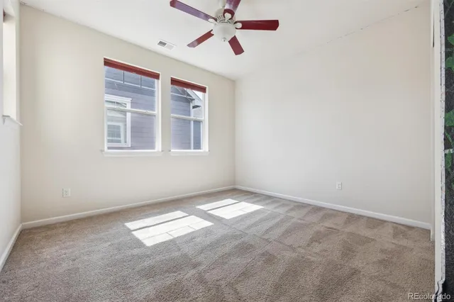 an empty room with windows and fan