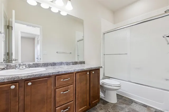 a bathroom with a granite countertop sink a toilet and a mirror