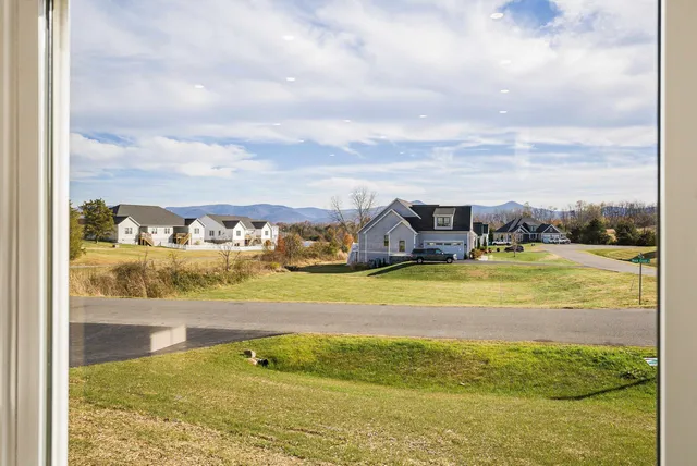 a view of an empty room with wooden floor and a ceiling fan