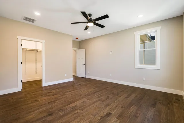 a view of empty room with wooden floor and fan