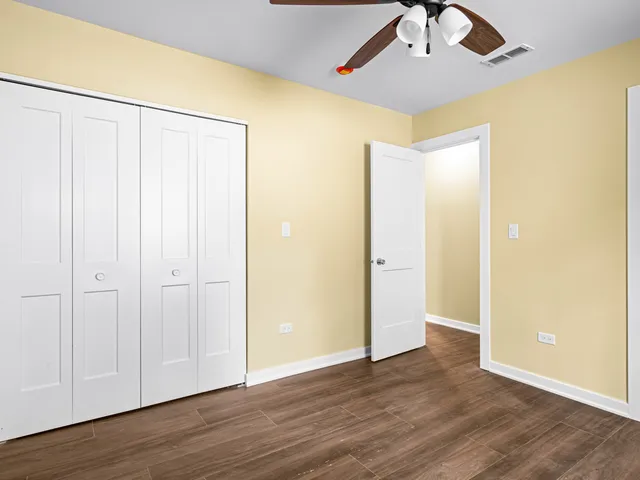 an empty room with wooden floor closet and windows