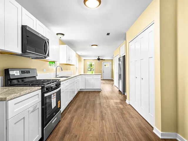 a large kitchen with stainless steel appliances granite countertop a stove and a wooden floors