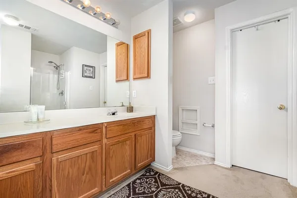 a spacious bathroom with a double vanity sink a mirror and a toilet