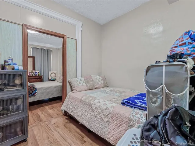 a bedroom with a bed a dresser and wooden floor