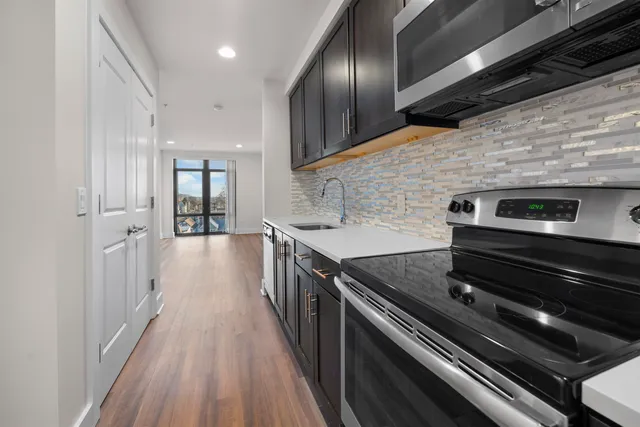 a hallway with wooden cabinets and stainless steel appliances