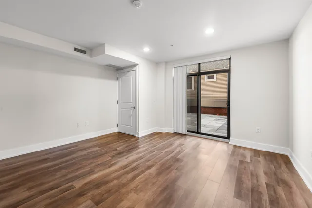 a view of an empty room with wooden floor and closet