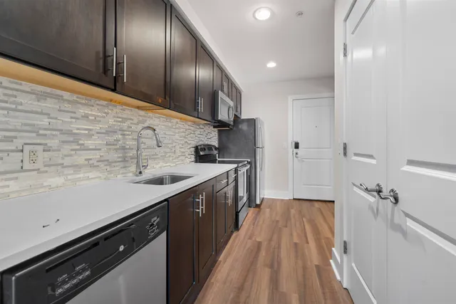 a kitchen with granite countertop stainless steel appliances a sink stove top oven and cabinets