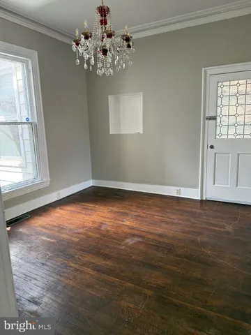 a view of an empty room with wooden floor and fan