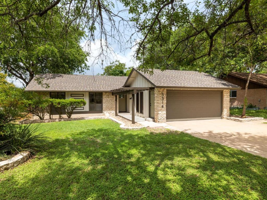 View of front of property featuring concrete driveway, an attached garage, roof with shingles, and a front lawn