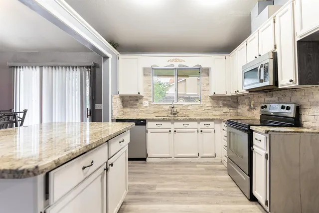 a kitchen with granite countertop stainless steel appliances a sink stove and cabinets