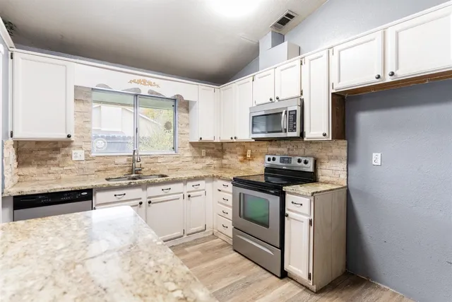 a kitchen with stainless steel appliances granite countertop a stove a sink and a microwave