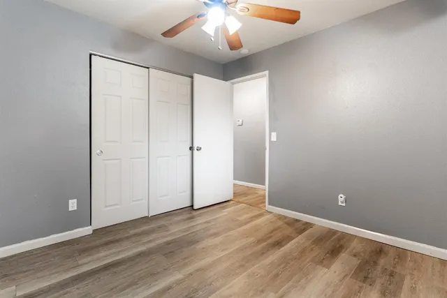 an empty room with wooden floor and chandelier fan