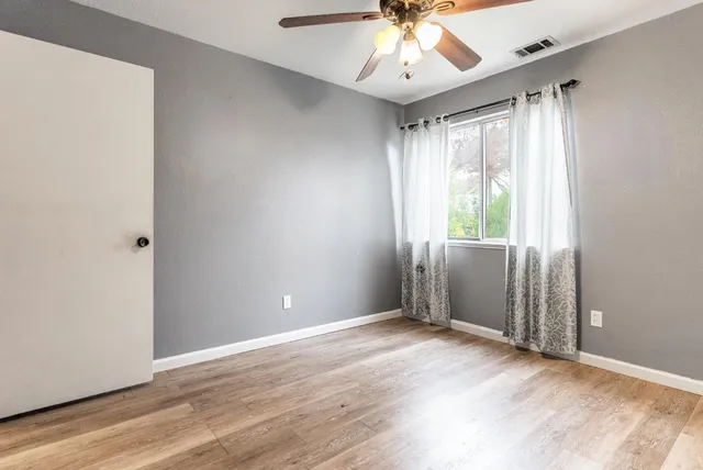 an empty room with wooden floor and windows
