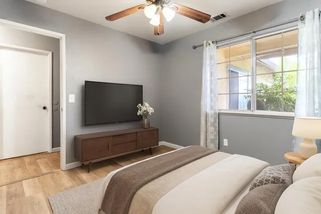 a bedroom with a large bed and a flat tv screen on dresser