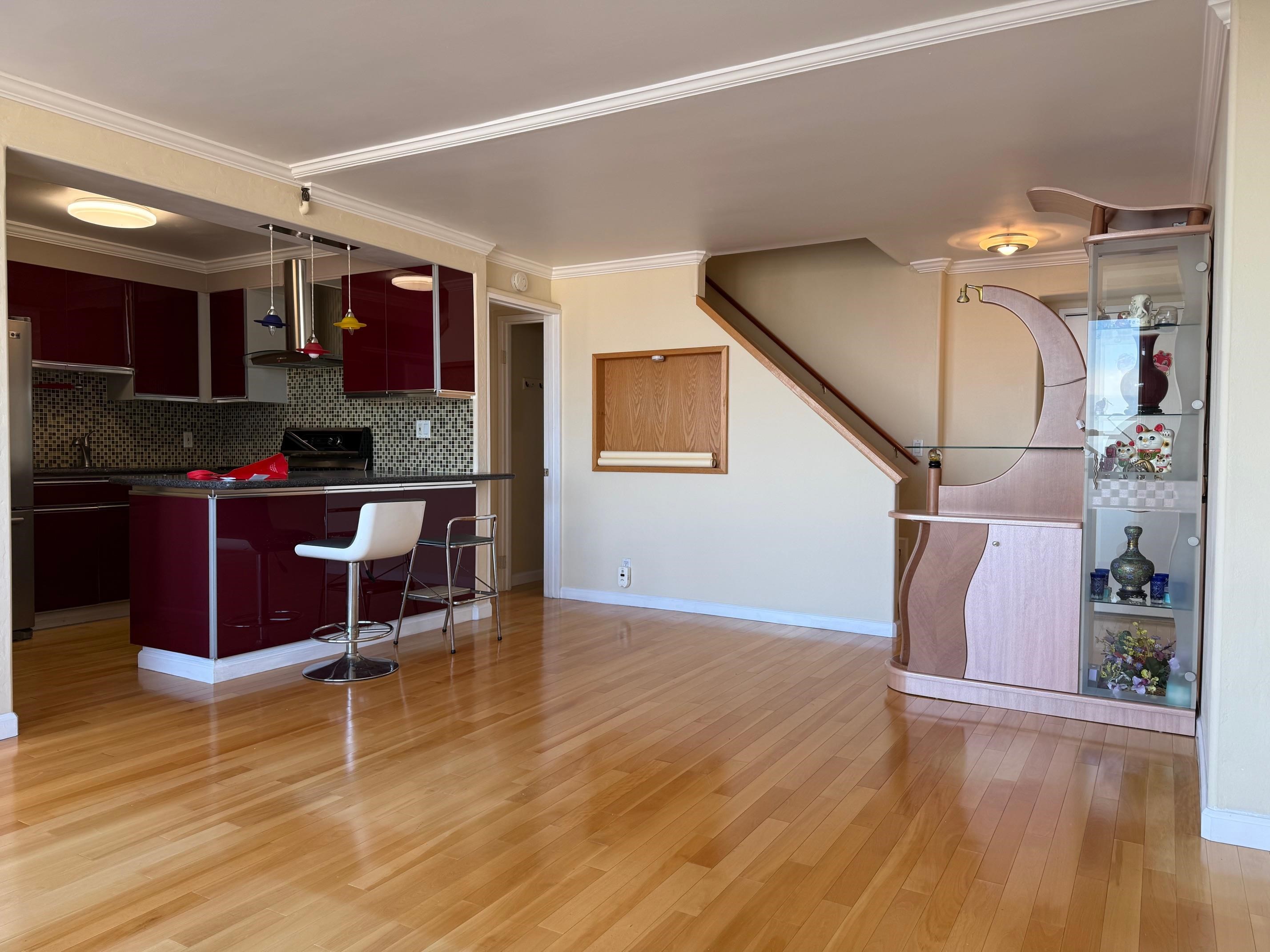 801 Franklin Street, Unit 1239 Oakland, CA 94607 - Photo 2 of 15 Kitchen featuring dark countertops, a kitchen bar, wall chimney range hood, decorative backsplash, and light wood finished floors