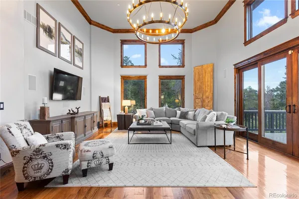 a living room with furniture a fireplace a chandelier and a flat screen tv