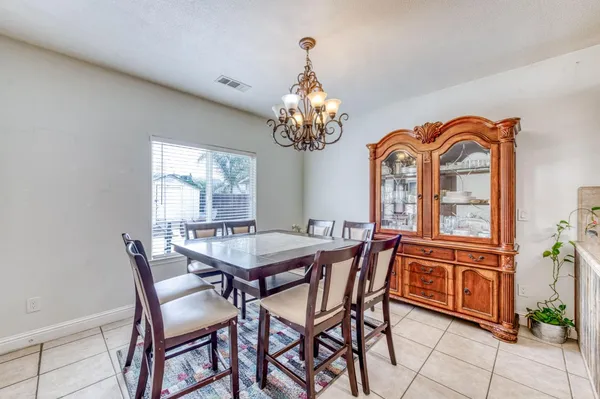 a kitchen with stainless steel appliances kitchen island granite countertop a refrigerator a stove top oven a sink a dining table and chairs with wooden floor
