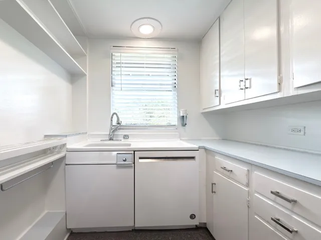 a kitchen with white cabinets appliances a sink and a window