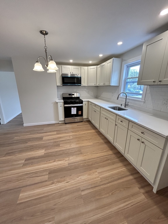 a kitchen with stainless steel appliances kitchen island granite countertop a sink dishwasher a stove and a refrigerator with wooden floor