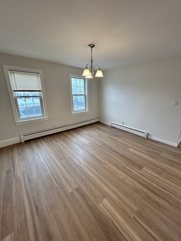 0 Main Street, Unit 1 Brockton, MA 02301 - Photo 4 of 9 an empty room with wooden floor windows and chandelier