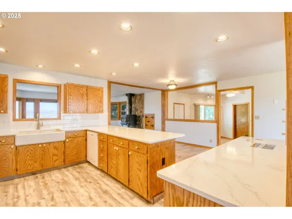 a view of open kitchen with kitchen island a sink wooden floor and a refrigerator