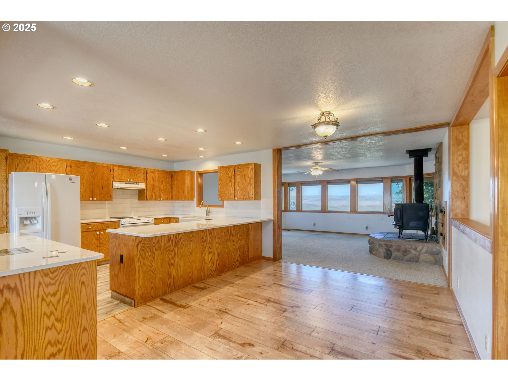72062 Westfield Boulevard Pendleton, OR 97801 - Photo 12 of 48 a view of open kitchen with kitchen island a sink wooden floor and a refrigerator
