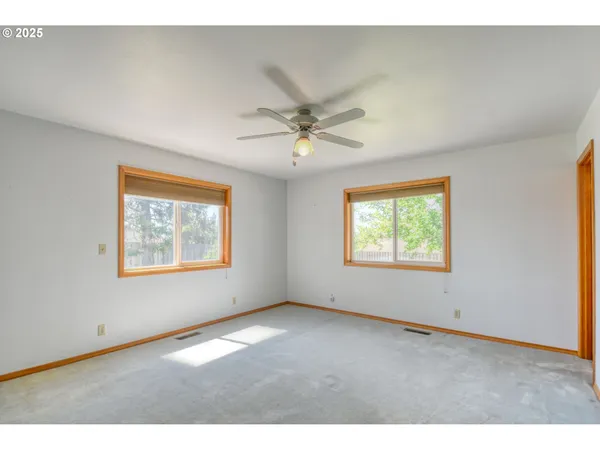 a view of an empty room with closet and a ceiling fan