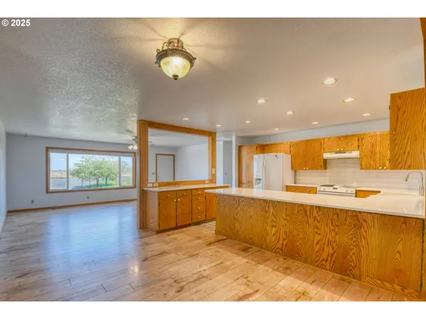 a kitchen with stainless steel appliances granite countertop a refrigerator a sink a stove and white cabinets with wooden floor