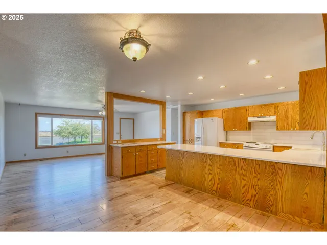 a kitchen with stainless steel appliances granite countertop a refrigerator a sink a stove and white cabinets with wooden floor