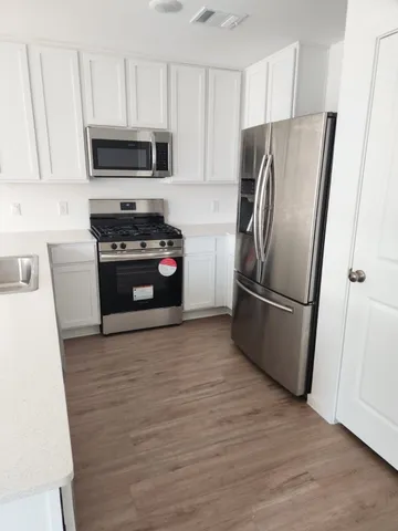 a kitchen with granite countertop a refrigerator and a stove top oven