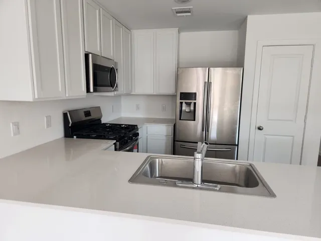 a kitchen with stainless steel appliances granite countertop a refrigerator a stove a microwave and a sink