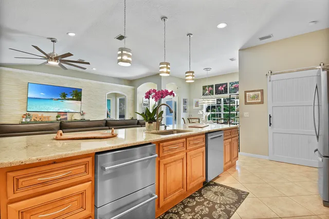 a kitchen with kitchen island granite countertop a sink a counter top space appliances and cabinets