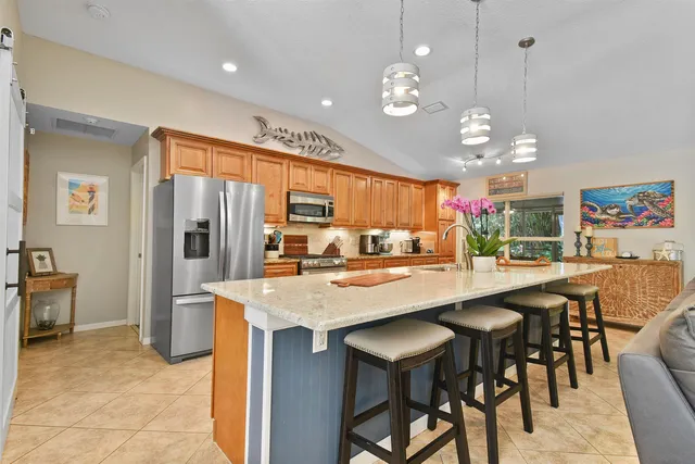 a kitchen with stainless steel appliances kitchen island granite countertop a table chairs and a refrigerator