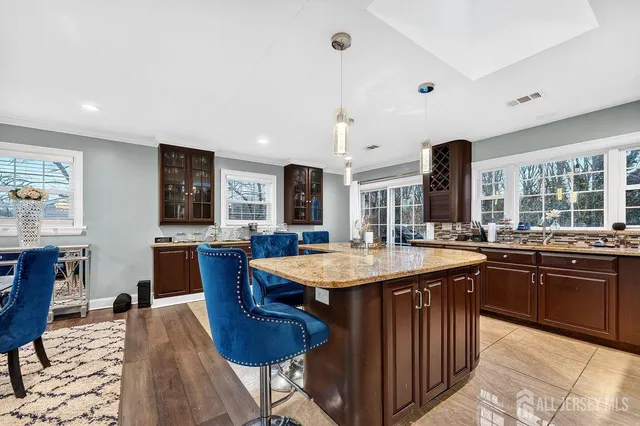 a dining hall with stainless steel appliances granite countertop a sink a stove a dining table and chairs with wooden floor