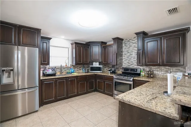 a kitchen with stainless steel appliances granite countertop a sink stove and refrigerator