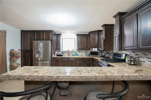 a kitchen with granite countertop stainless steel appliances a sink and refrigerator