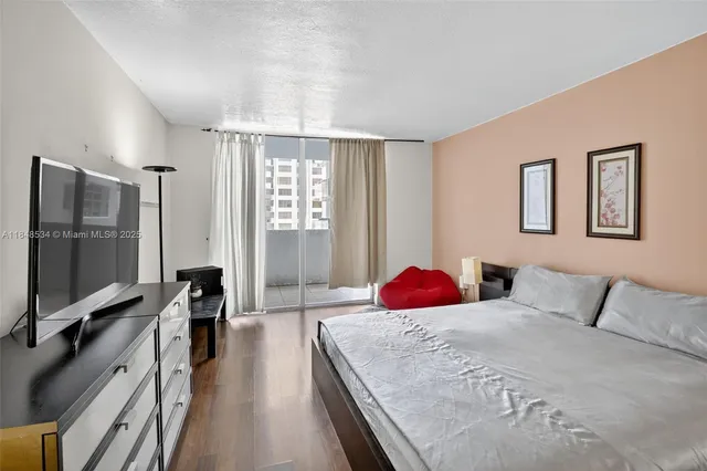 a bedroom with a large bed and a flat tv screen on dresser