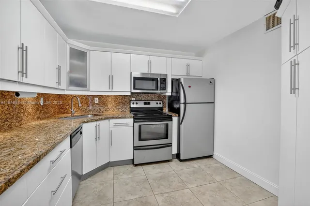 a kitchen with granite countertop a refrigerator and a stove top oven