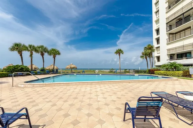 a front view of a building with garden and trees