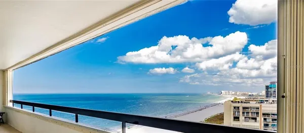 a front view of a building with garden and trees