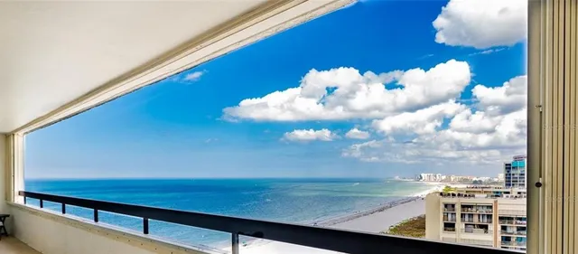 a front view of a building with garden and trees